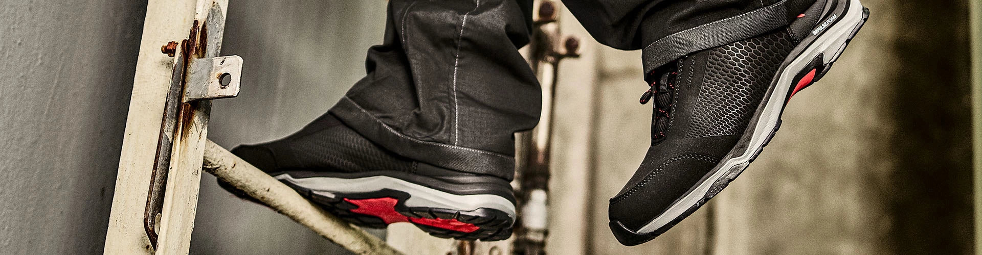 Schwarzer Berufsschuh VIALE BLACK LOW O1 von ALBATROS® im Einsatz auf einer Leiter, mit roter Sohle und atmungsaktivem Obermaterial